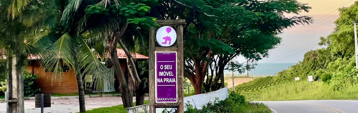 Placa da MAXXVIDA Imóveis à beira da CE-346, na entrada de Flecheiras, Trairi
