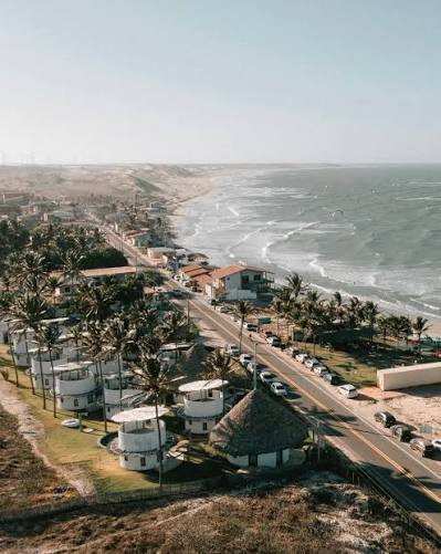 Vista aérea da orla de Emboaca com a estrada paralela à praia, dunas e turbinas de vento ao fundo