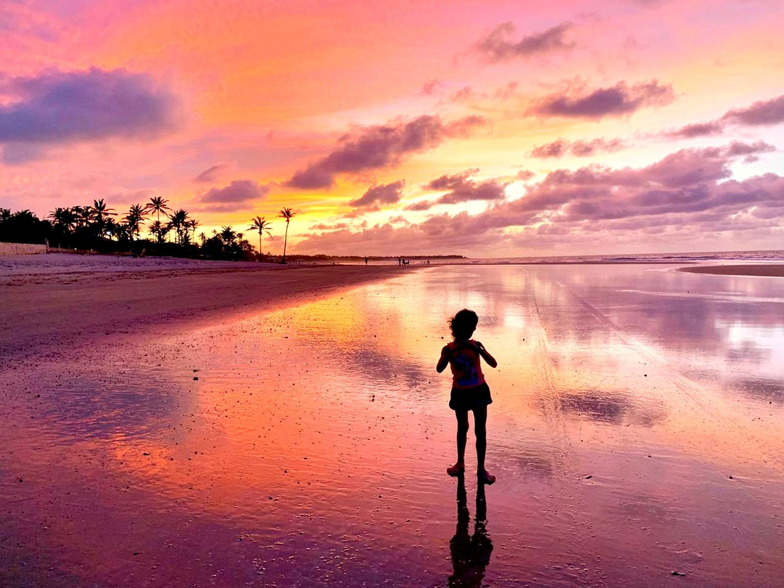 Pôr do sol dourado refletido na areia molhada da praia de Flecheiras, no litoral do Ceará