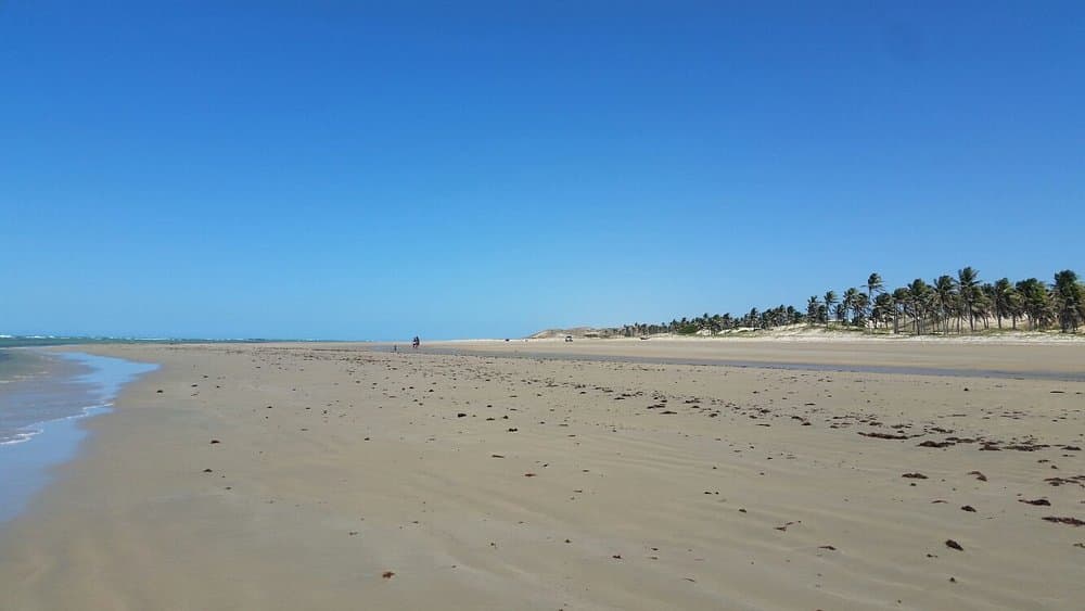 Faixa de areia larga e praticamente vazia na praia de Mundaú durante a maré baixa