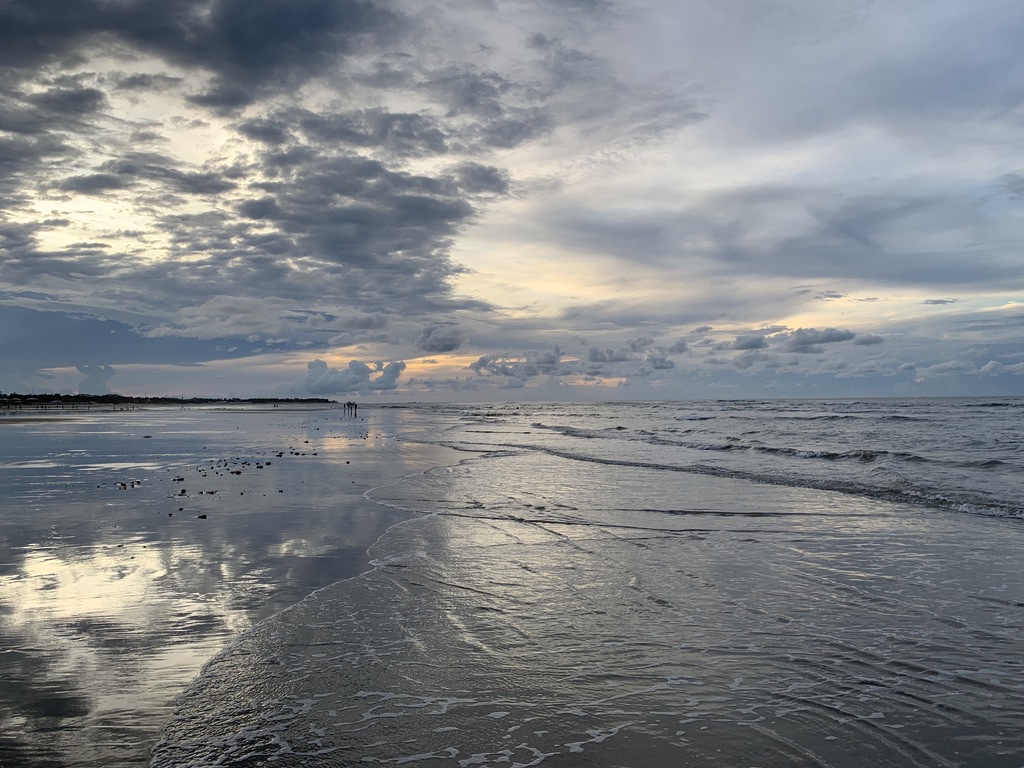Piscinas de água transparente na maré baixa em Guajiru, com reflexo do céu na areia molhada